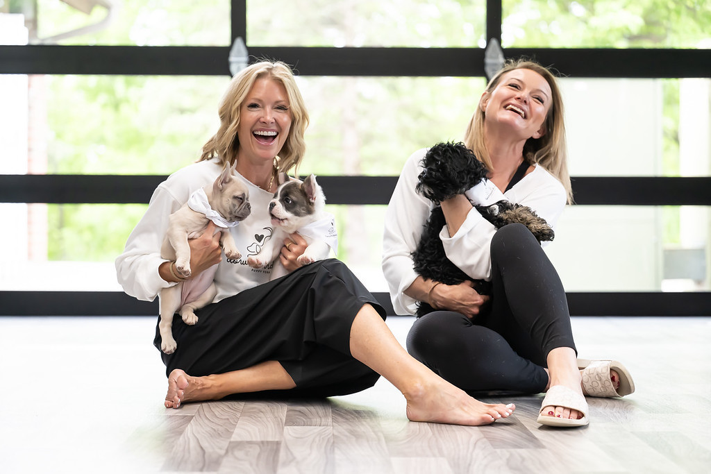 Downward Dogs founders laughing together while holding puppies in the studio